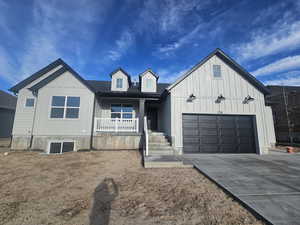 Modern farmhouse style home with covered porch, board and batten siding, driveway, and an attached garage