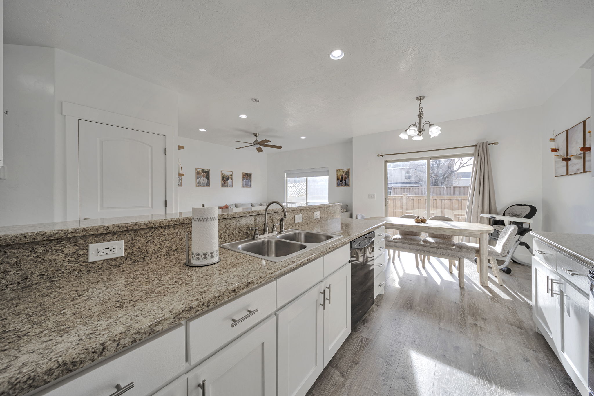 Kitchen featuring white cabinets, light wood-type flooring, a chandelier, light stone countertops, and ceiling fan