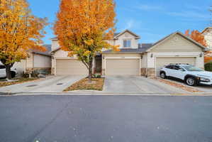View of front of property with a garage, driveway, stone siding, and roof mounted solar panels