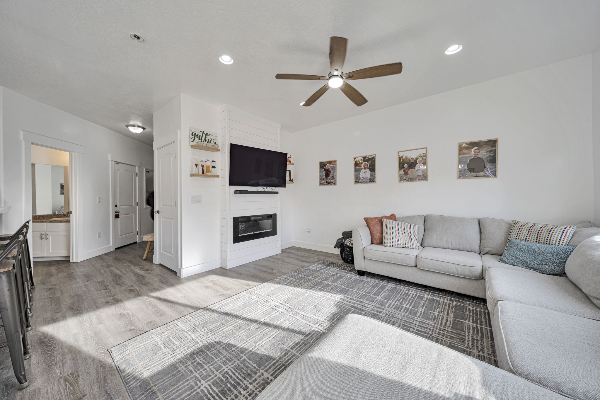 Living area featuring light wood-type flooring, a fireplace, ceiling fan, and recessed lighting
