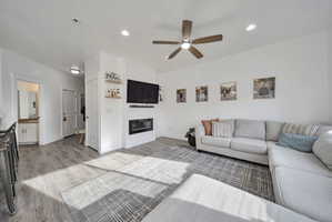Living area featuring light wood-type flooring, a fireplace, ceiling fan, and recessed lighting