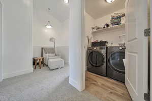 Laundry area featuring vaulted ceiling, washer and clothes dryer, and light carpet