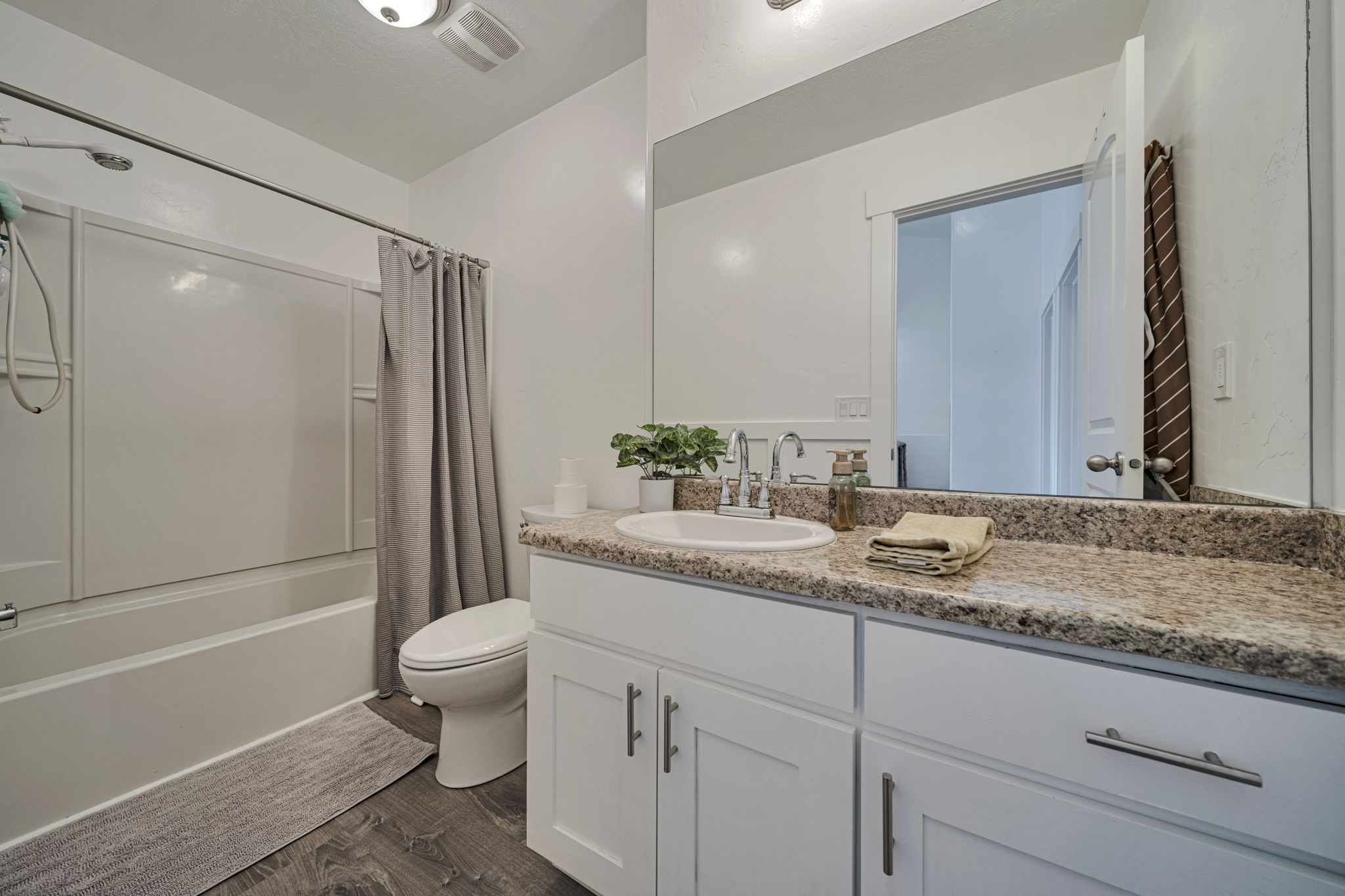 Bathroom with vanity, dark wood-type flooring, and shower / bathtub combination with curtain