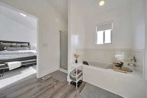 Ensuite bathroom with a shower stall, a bath, and wood finished floors