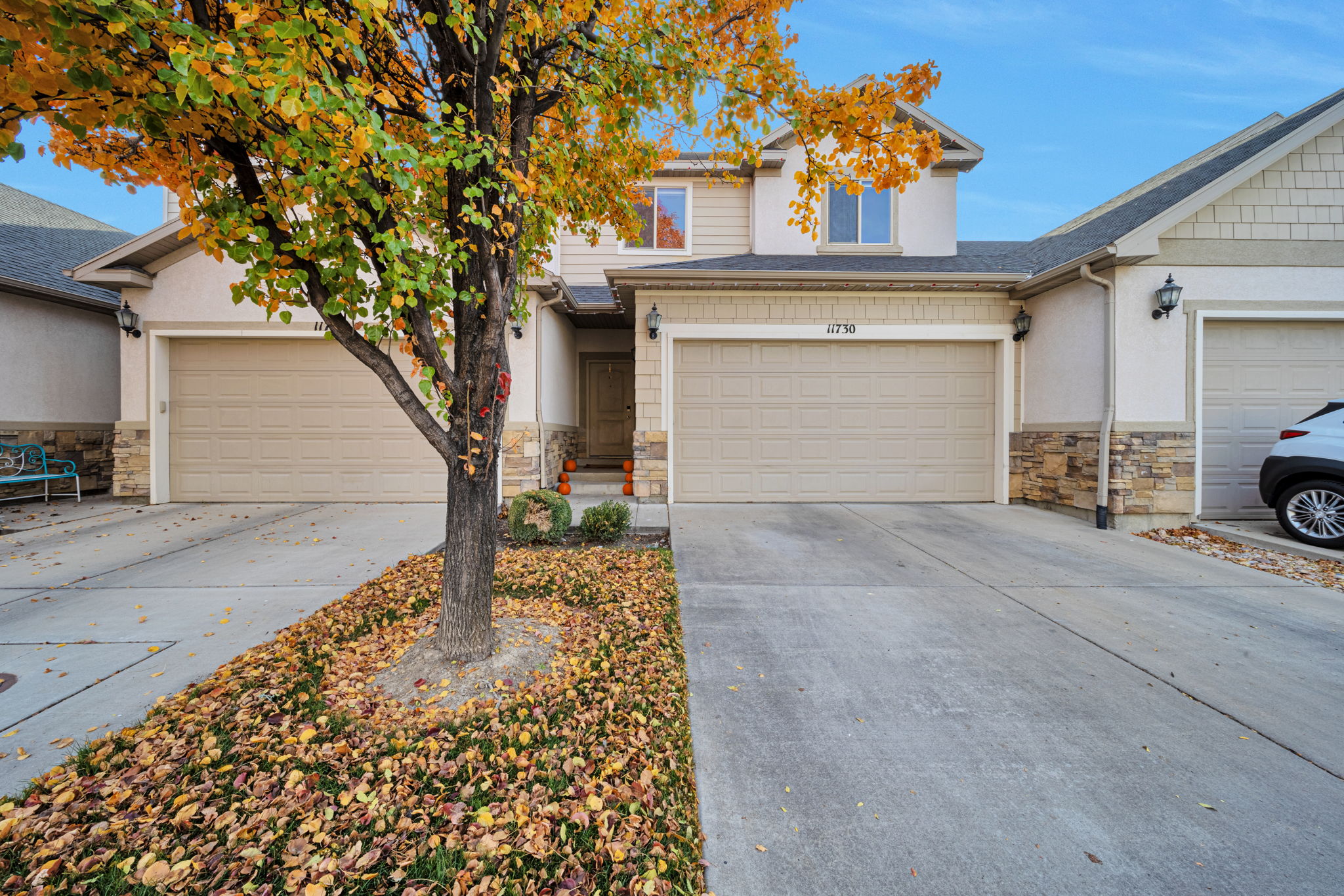 View of front of property with stone siding, driveway, and stucco siding