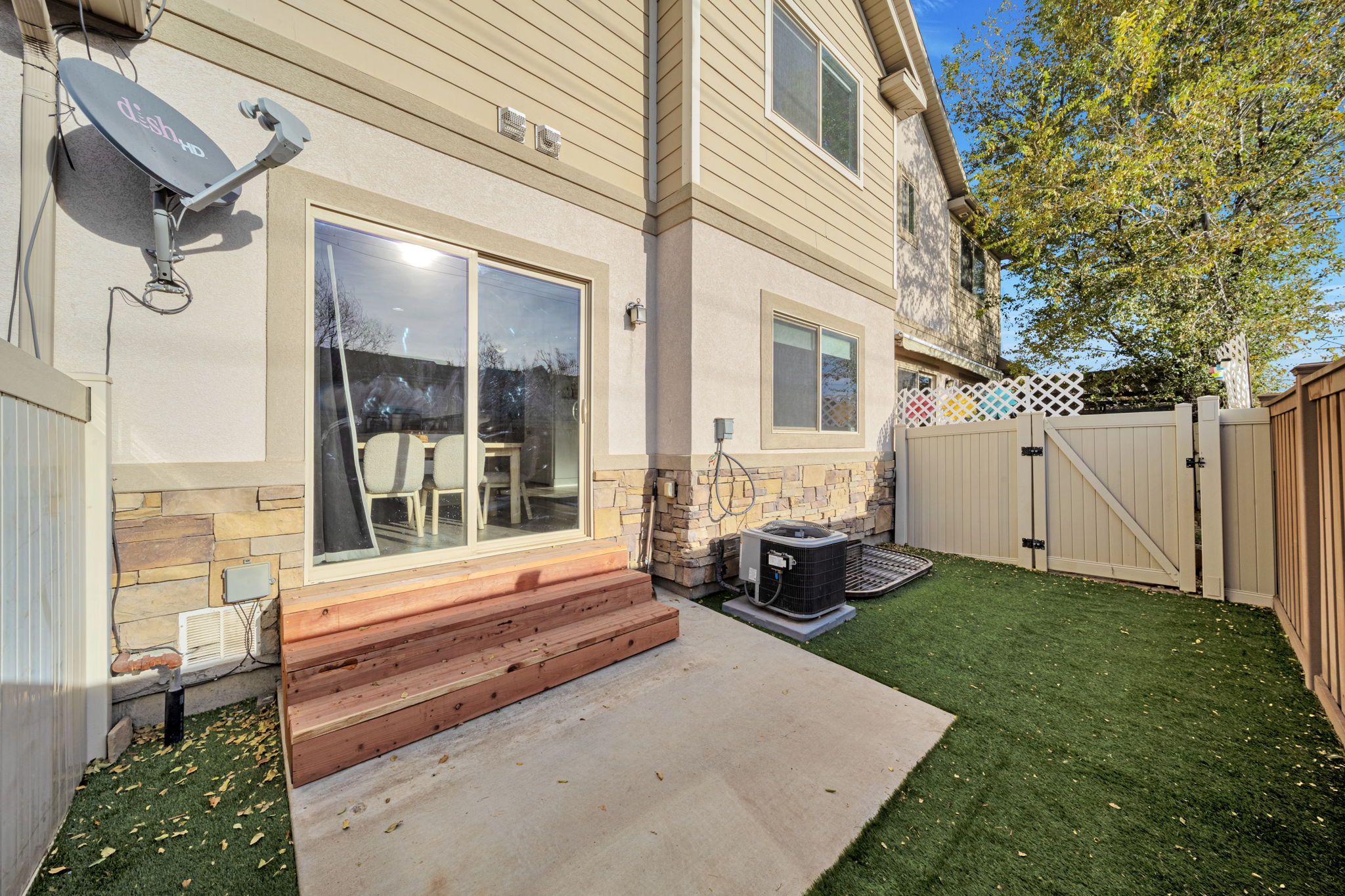 View of exterior entry featuring a gate, a patio area, stone siding, and stucco siding