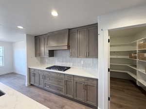 Kitchen with light stone countertops, recessed lighting, decorative backsplash, stainless steel gas cooktop, and light wood-style flooring