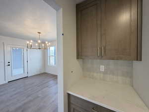 Kitchen featuring light stone countertops, light wood-style floors, suspended lighting, a textured ceiling, and dark wood finish cabinets