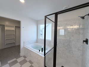 Full bath with a spacious closet, a marble finish shower, light floors, a bath, and recessed lighting