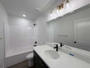 Bathroom with vanity, tub / shower combination, and dark wood-style flooring