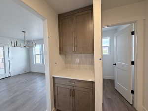 Kitchen featuring dark wood finished floors, hanging lights, healthy amount of natural light, and backsplash