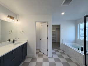 Full bath featuring vanity, a spacious closet, light floors, a garden tub, and recessed lighting