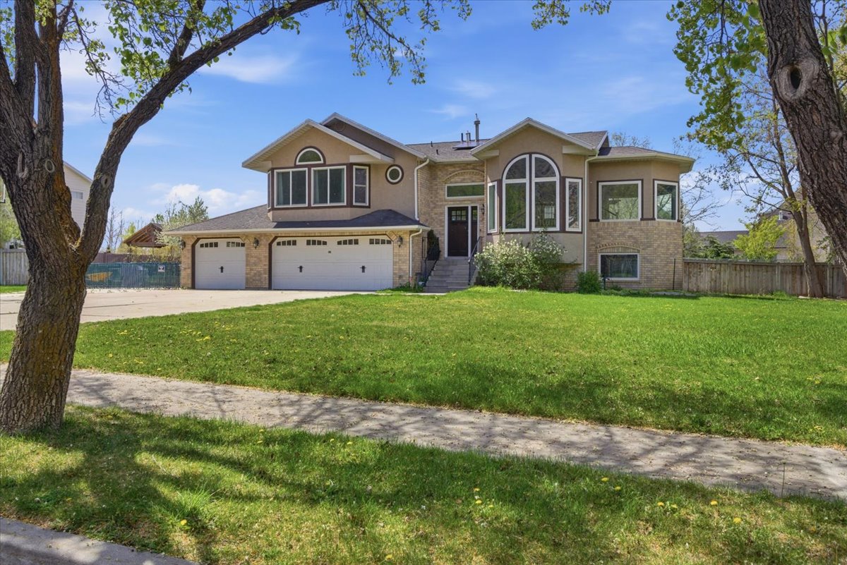 Raised ranch with brick siding, driveway, a garage, and stucco siding