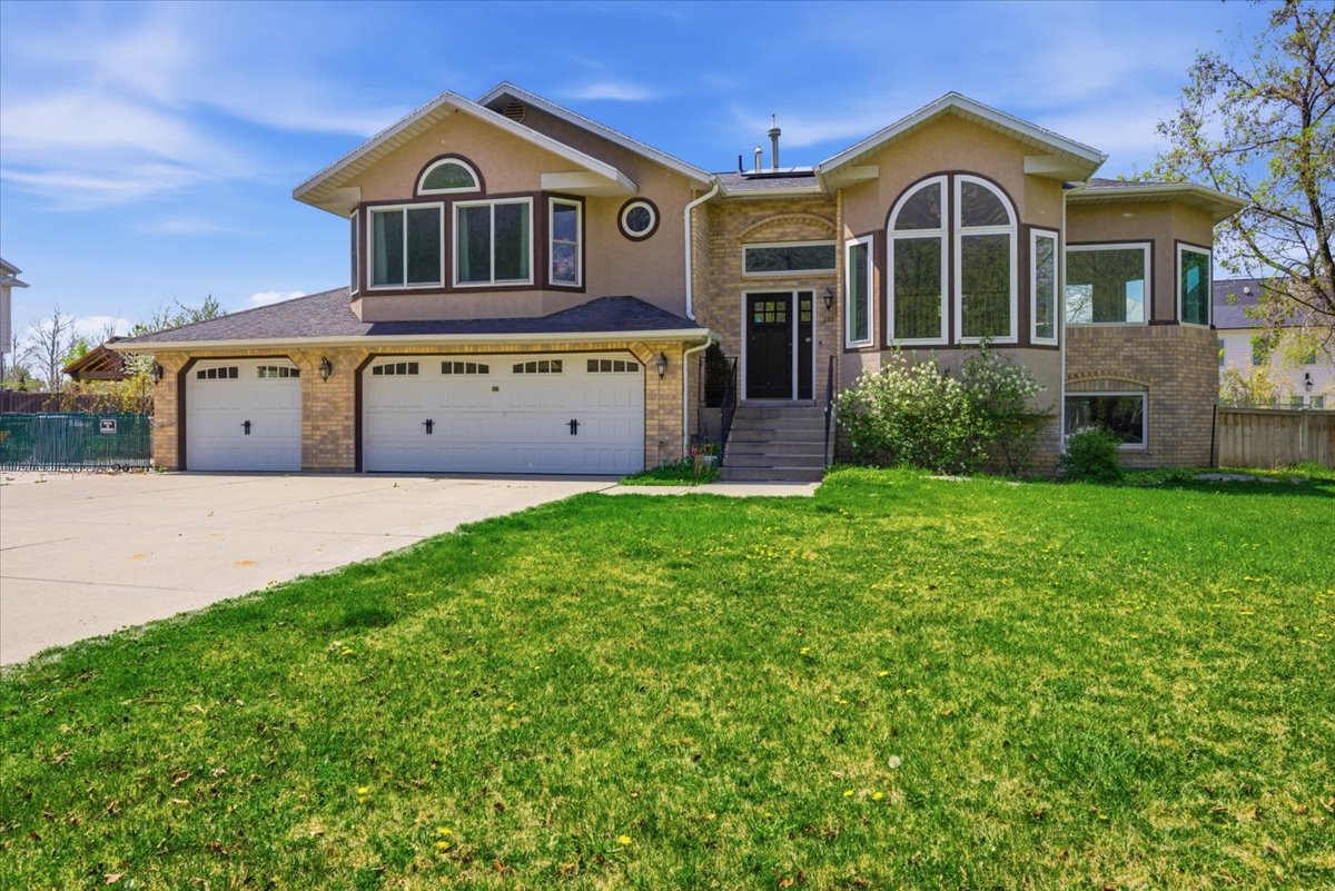 View of front of house featuring brick siding, driveway, a garage, and stucco siding