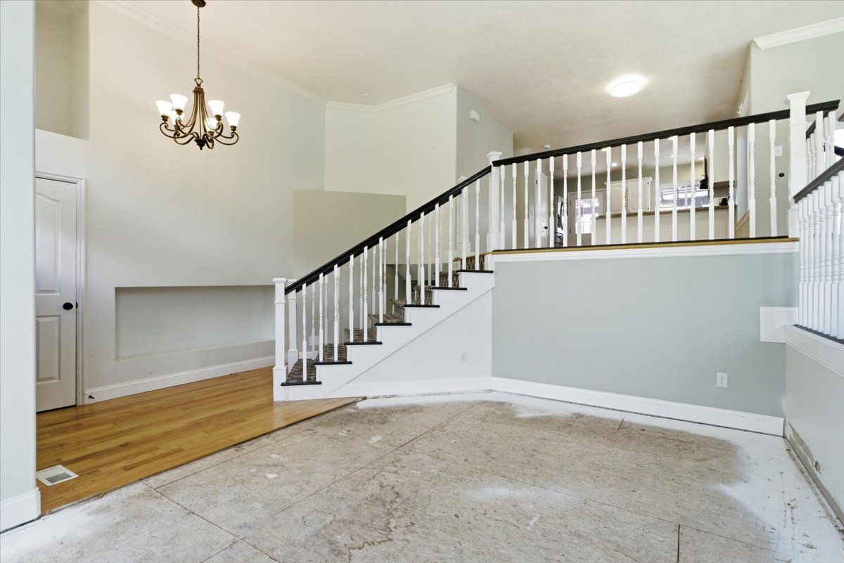 Stairway with crown molding, hanging lights, and wood finished floors