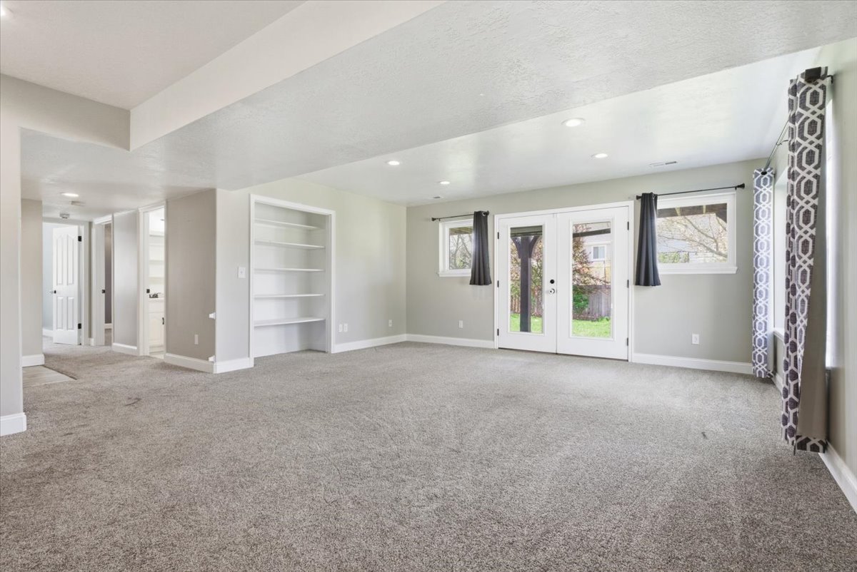 Unfurnished room with french doors, built in features, light colored carpet, and recessed lighting