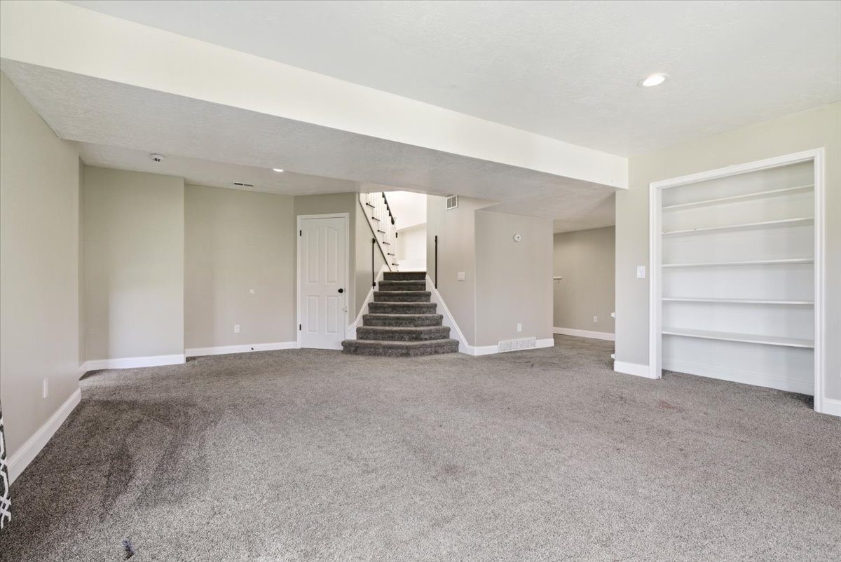 Unfurnished room with built in features, light colored carpet, and recessed lighting