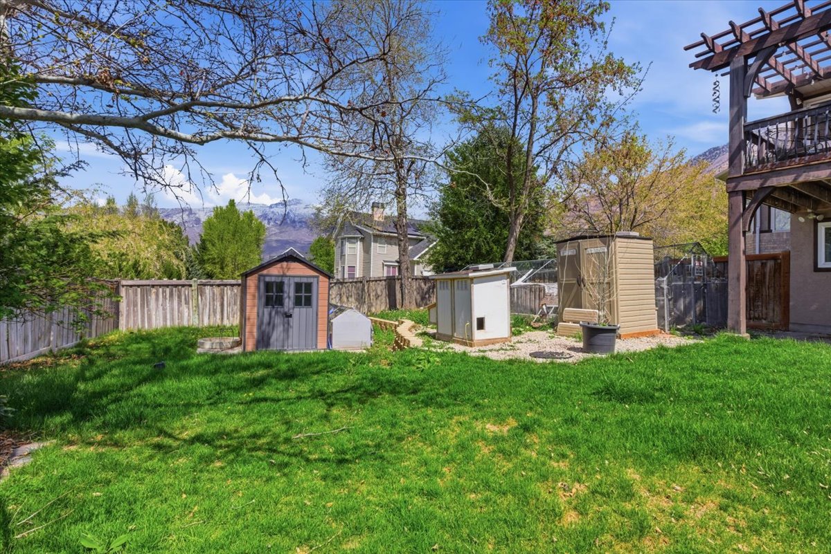 Fenced backyard featuring a storage unit and a pergola