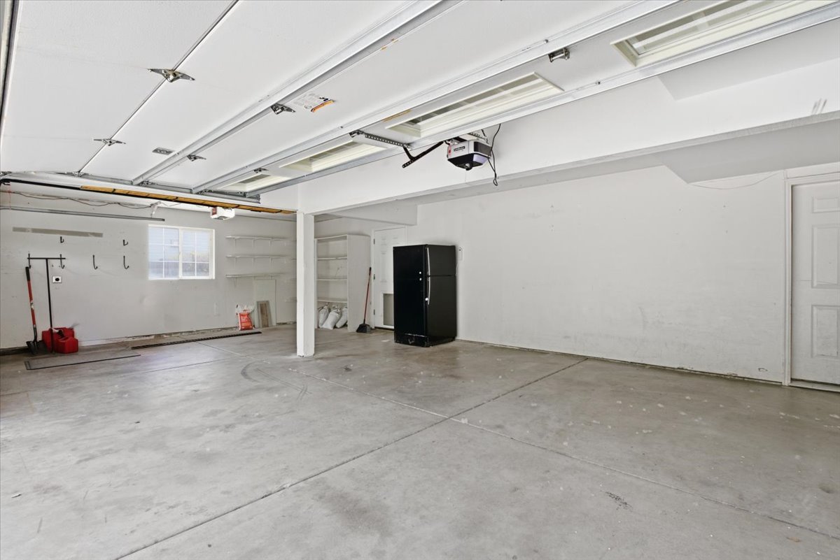 Garage featuring freestanding refrigerator and a garage door opener