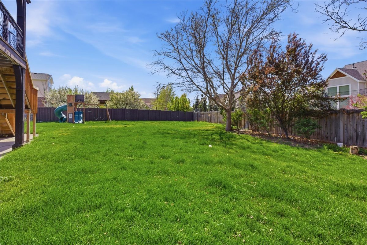 Fenced backyard featuring a playground