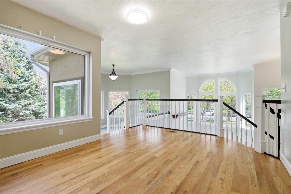 Unfurnished room with light wood finished floors, ornamental molding, and a textured ceiling