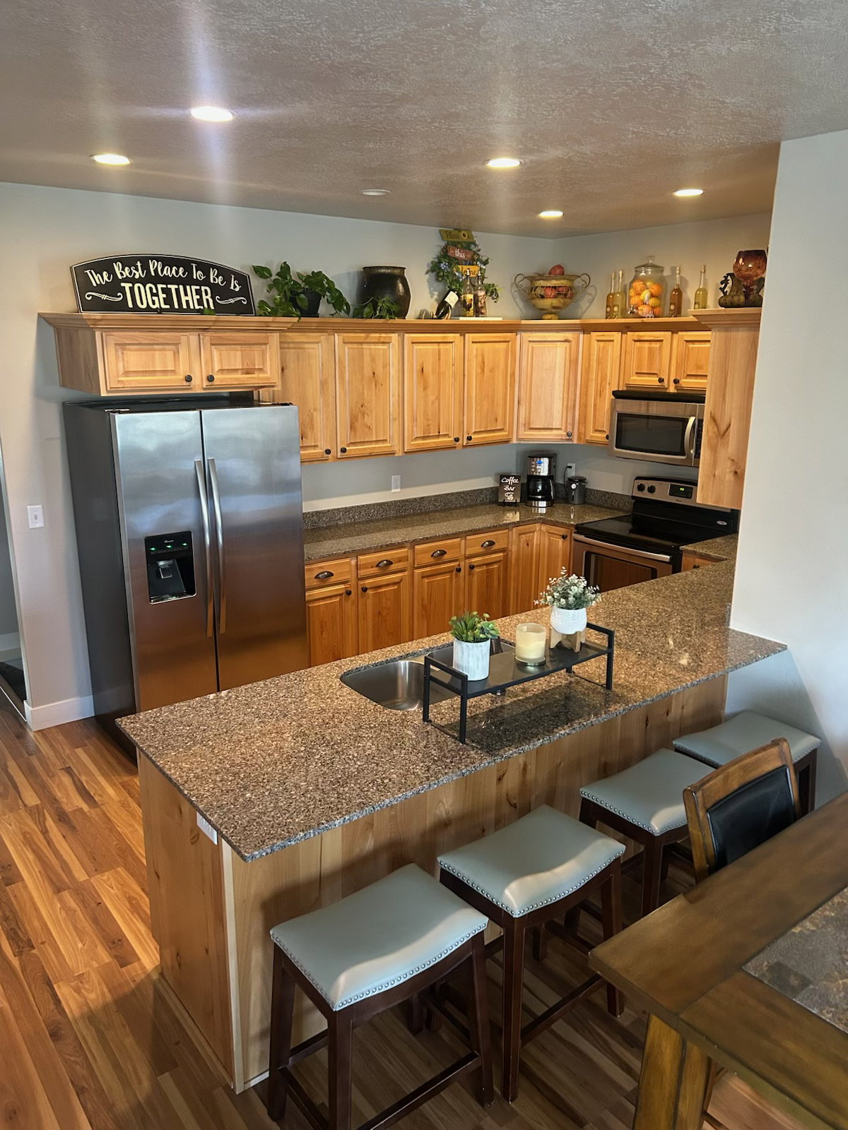 Kitchen featuring a kitchen breakfast bar, dark stone counters, a textured ceiling, stainless steel appliances, and recessed lighting