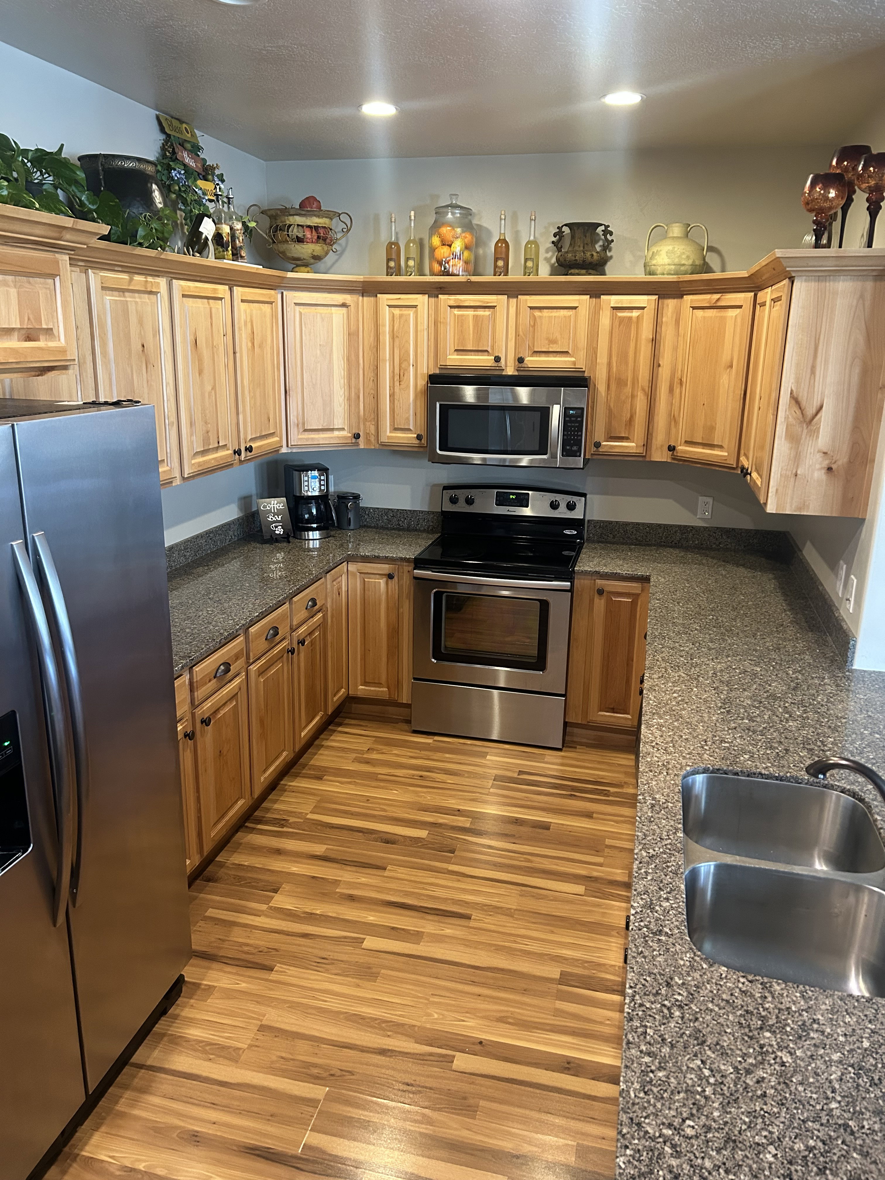 Kitchen with stainless steel appliances, dark stone countertops, light wood finished floors, a textured ceiling, and wood finish cabinets