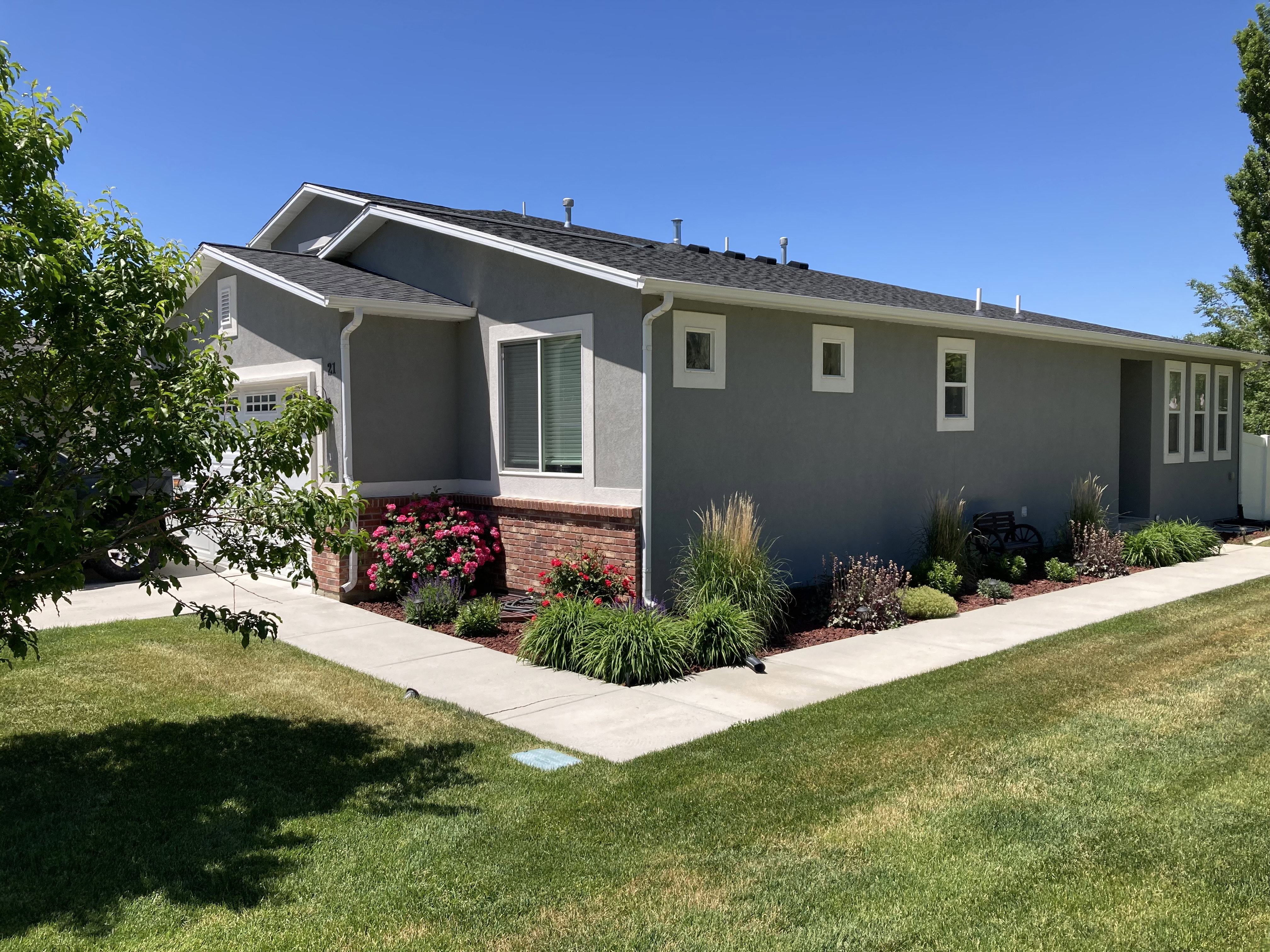 View of side of property with a yard, brick siding, stucco siding, and a garage