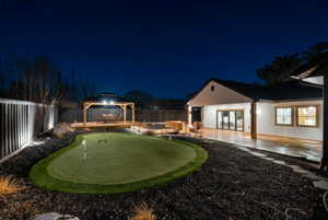 Yard at night with a gazebo, a putting green, a patio, and a fenced backyard
