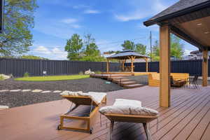 Wooden deck with a gazebo, a fenced backyard, and a putting area