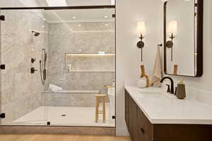Bathroom featuring vanity, a marble finish shower, and light wood-type flooring