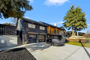 View of front of property with brick siding, driveway, a chimney, a garage, and a balcony