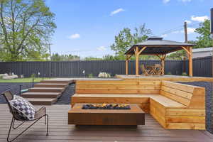 Wooden deck with a fenced backyard, a gazebo, an area to practice putting, and a fire pit