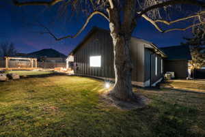 Property exterior at twilight with board and batten siding and a putting area