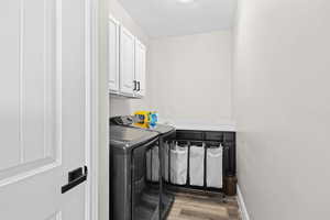 Laundry area with cabinet space, light wood-type flooring, and independent washer and dryer