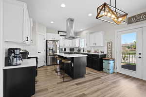 Kitchen featuring dual tone cabinets, a kitchen bar, a kitchen island, stainless steel appliances, and light wood-style floors