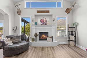 Sitting room with a high ceiling, light wood-type flooring, and a tiled fireplace