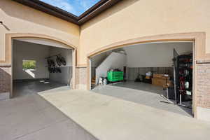 Entrance to property featuring stucco siding, driveway, a patio, and an attached garage