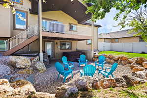 Rear view of house with a patio, a hot tub, stucco siding, a deck, and a gate