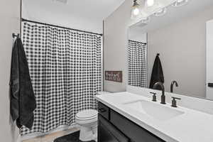 Full bath featuring vanity, a shower with shower curtain, and light wood-style flooring