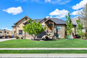 Craftsman-style house with stone siding, a front yard, and stucco siding