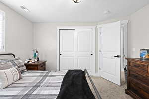 Bedroom featuring a closet, light carpet, and a textured ceiling