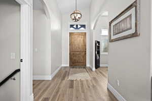 Entrance foyer with lofted ceiling, suspended lighting, light wood-type flooring, and arched walkways