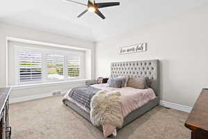 Carpeted bedroom with a tray ceiling and a ceiling fan