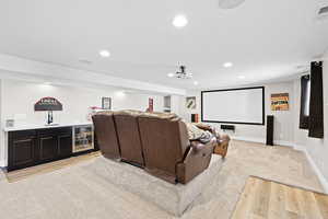 Home theater room featuring recessed lighting, beverage cooler, bar with sink, and light wood-style flooring