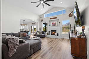 Living area featuring arched walkways, light wood-style flooring, lofted ceiling, a ceiling fan, and recessed lighting