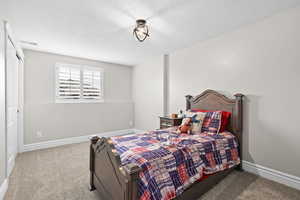 Bedroom with light colored carpet and a textured ceiling