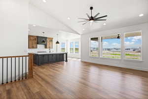 Unfurnished living room with lofted ceiling, dark wood-style flooring, and a ceiling fan