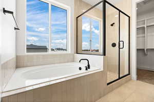 Bathroom featuring a walk in closet, a garden tub, a stall shower, light tile patterned floors, and plenty of natural light