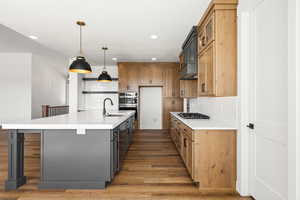 Two tone kitchen with dual tone cabinets, decorative backsplash, a large island, a breakfast bar, and light wood-style flooring